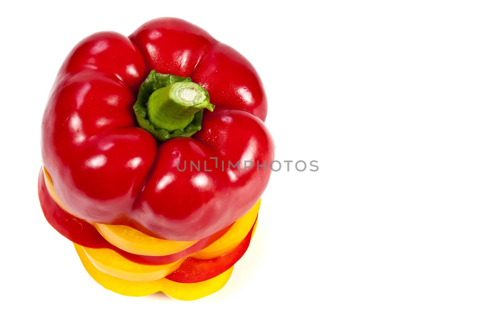 Slices of red and yellow sweet peppers stacked together on a white with blank text message copy space