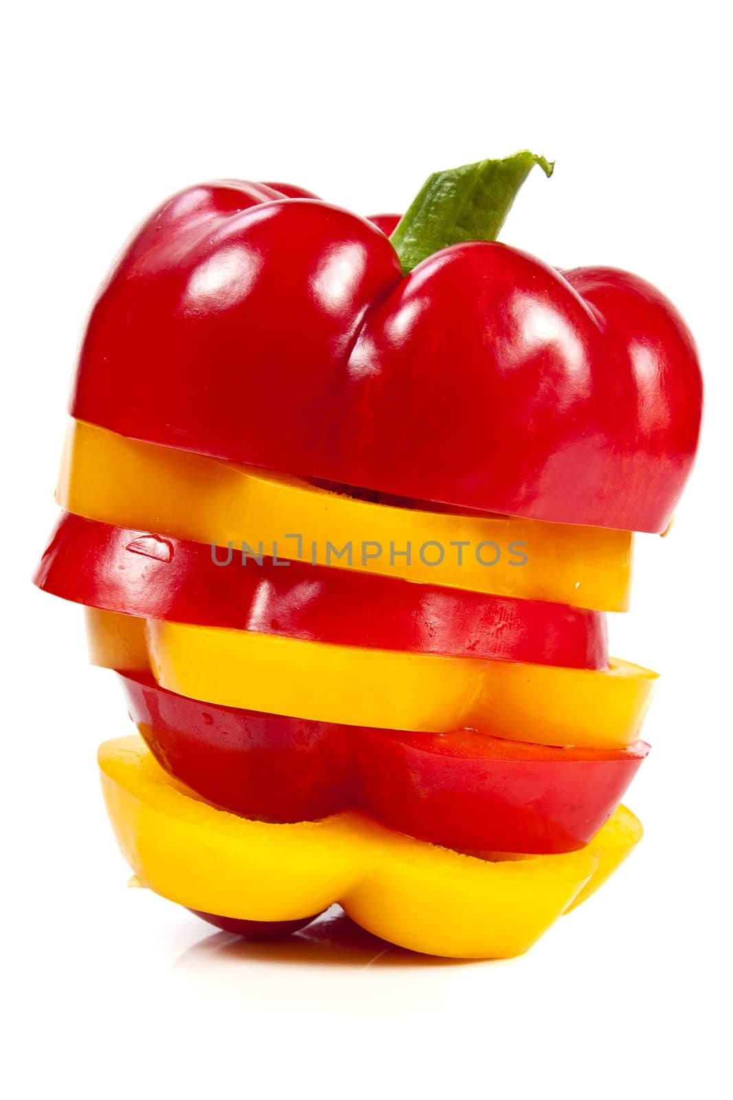 Slices of red and yellow sweet peppers stacked together on a white