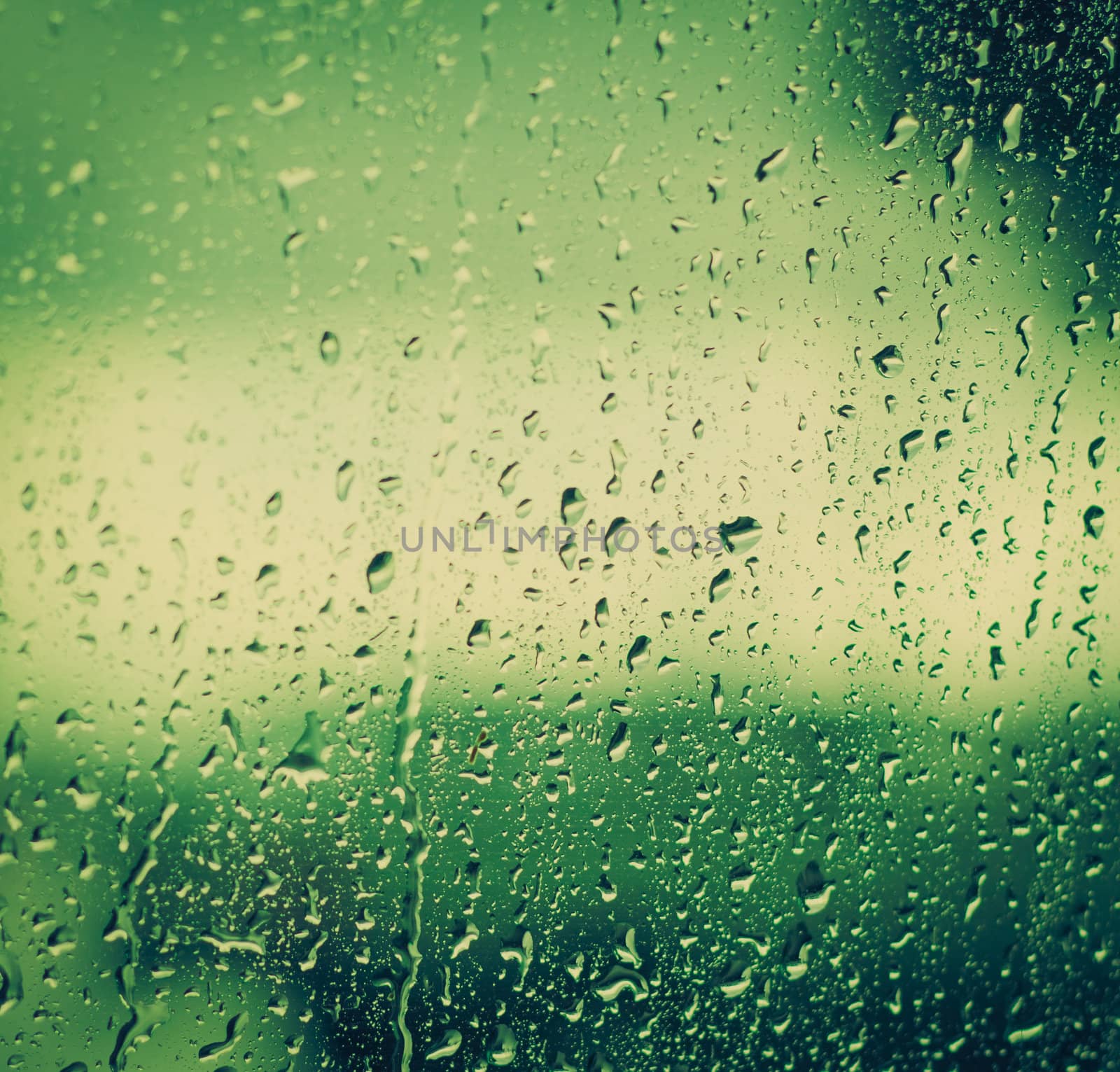 Drops of rain on glass on background of cloudy sky