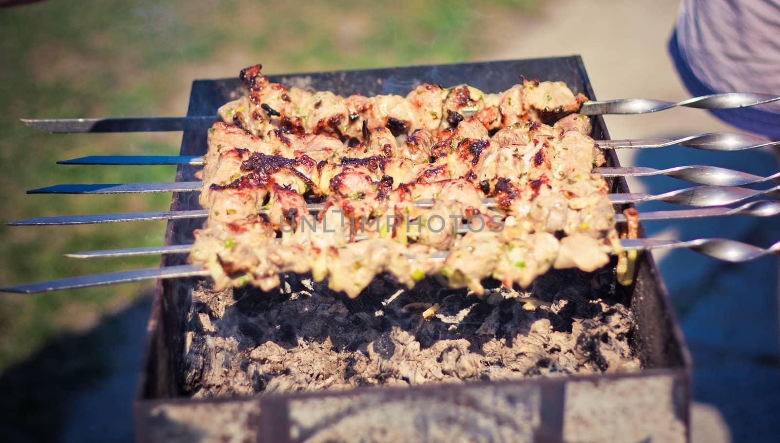 shish kebab in process of cooking on open fire outdoors by ryhor