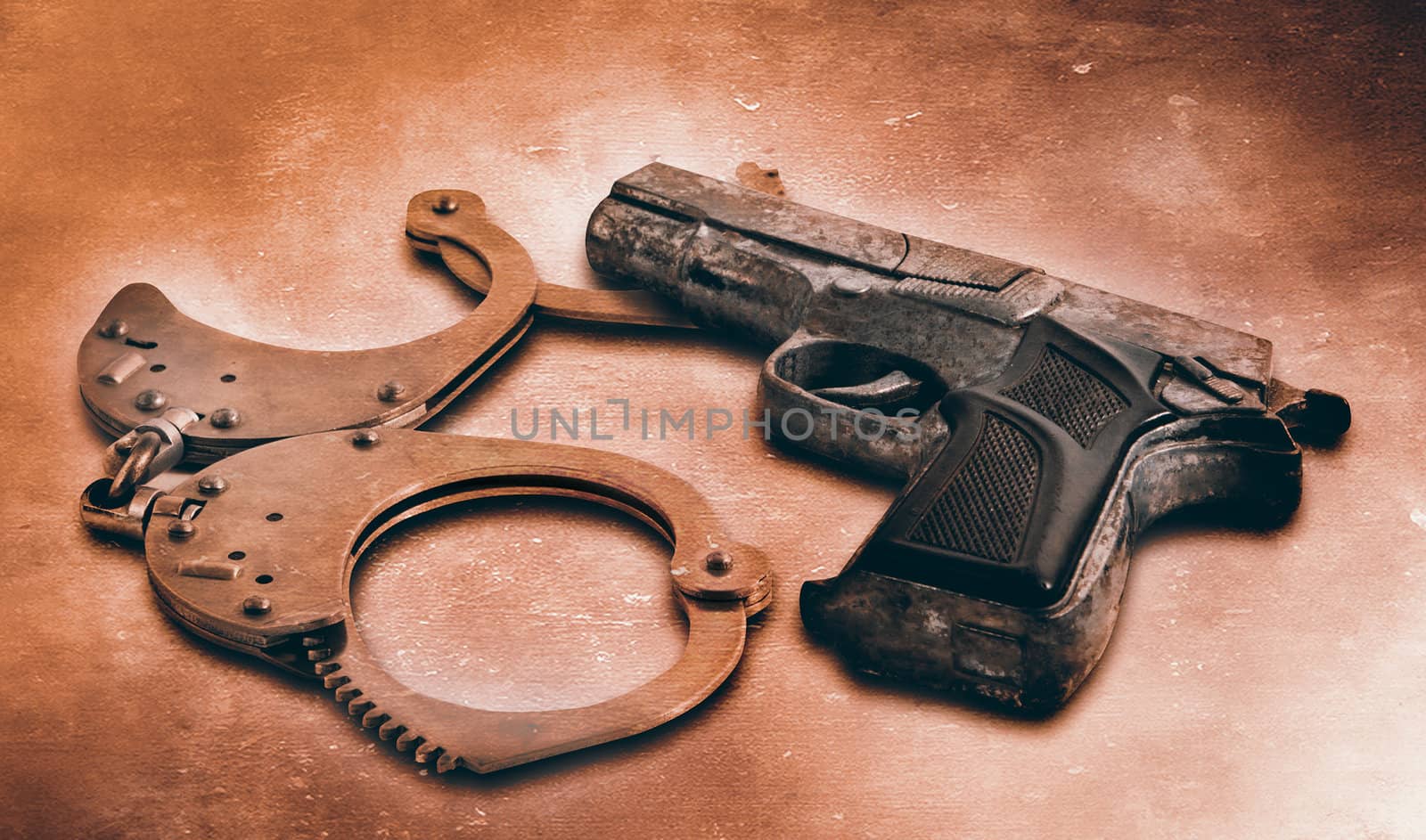 Gun and handcuffs on table. Photo in old color image style by Zhukow