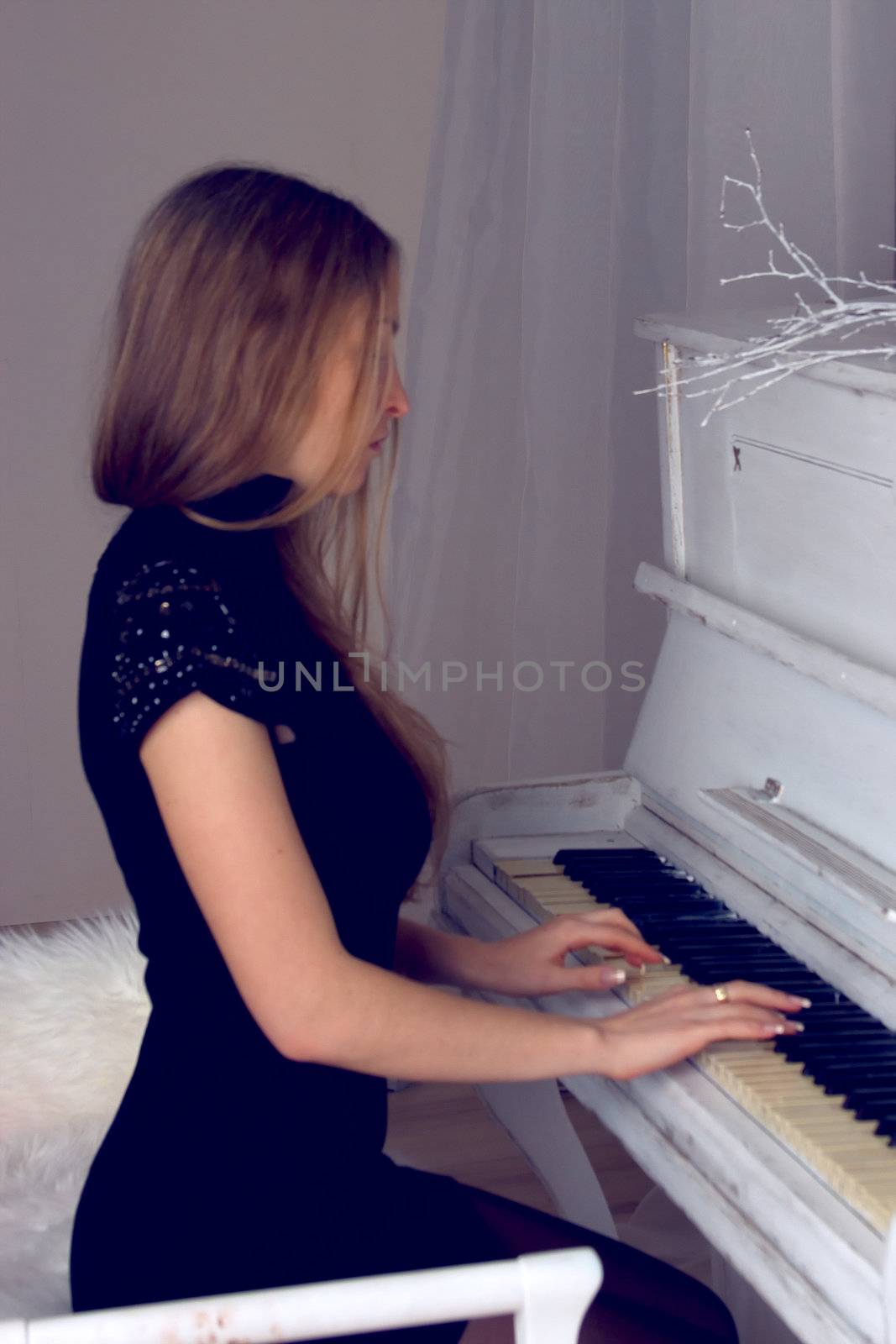girl with blond long  hair in  dress playing white piano