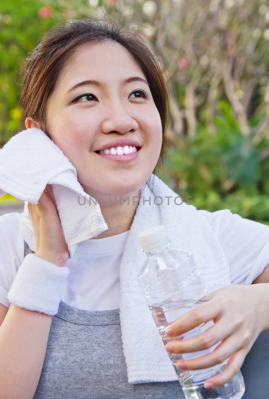 Asian woman wiping sweat with a towel after exercising by Myimagine