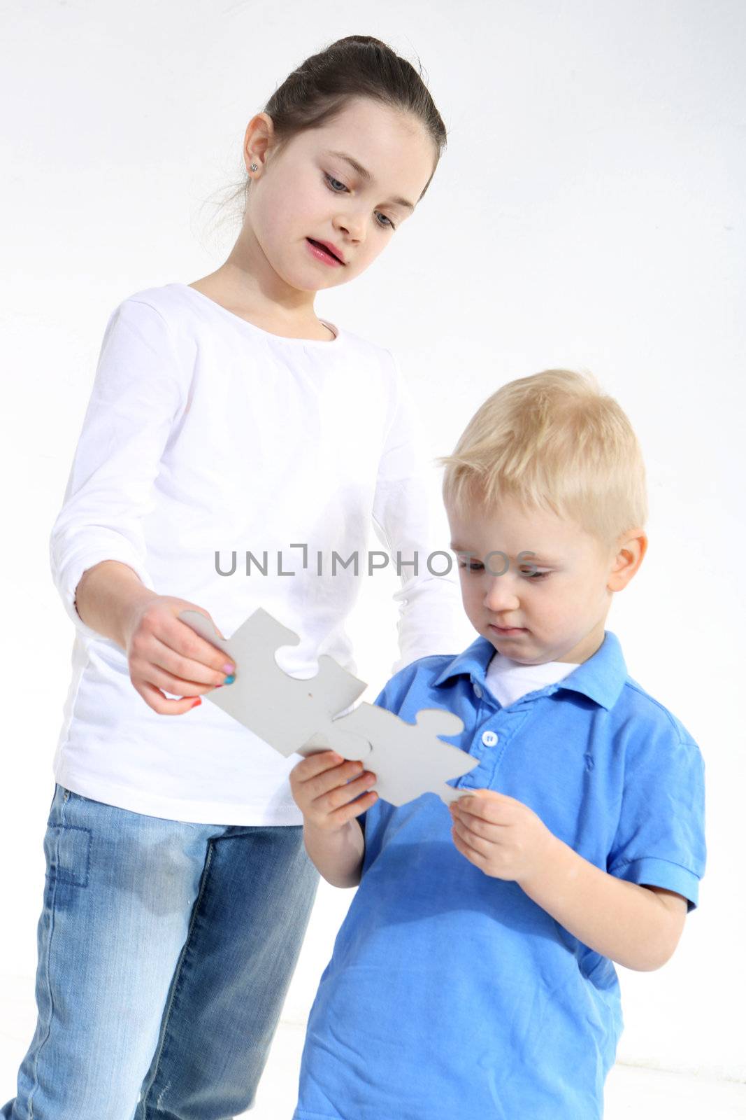 Sister and brother play with puzzle pieces isolated on white