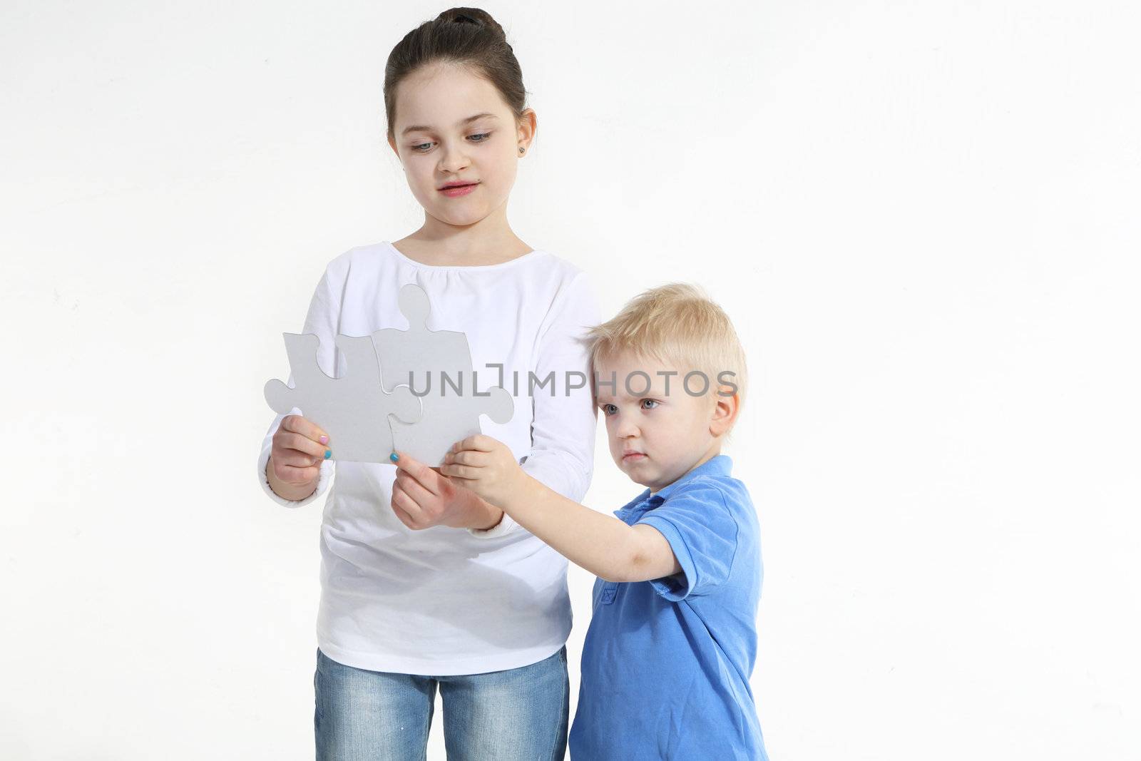 Sister and brother play with puzzle pieces isolated on white