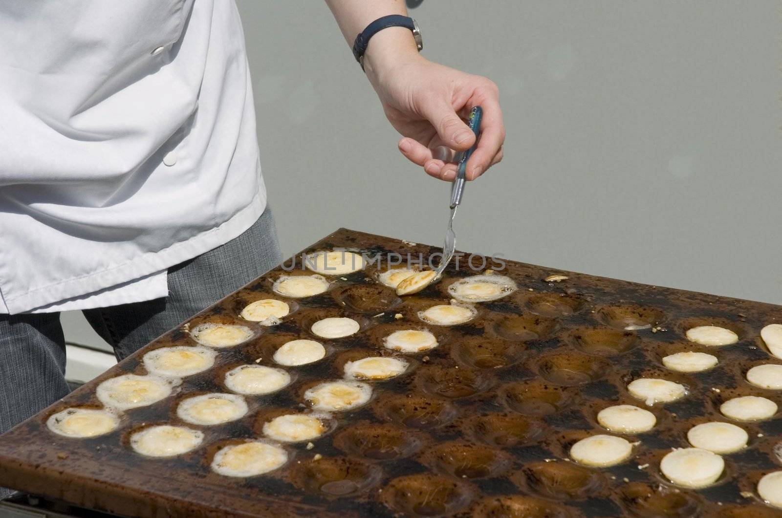 Person baking small Dutch pancakes