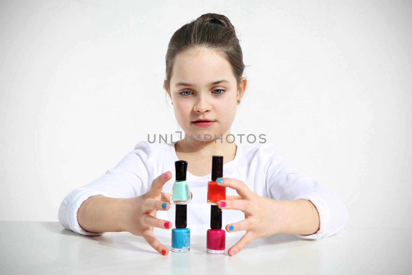 Little girl builds a pyramid using nail polishes
