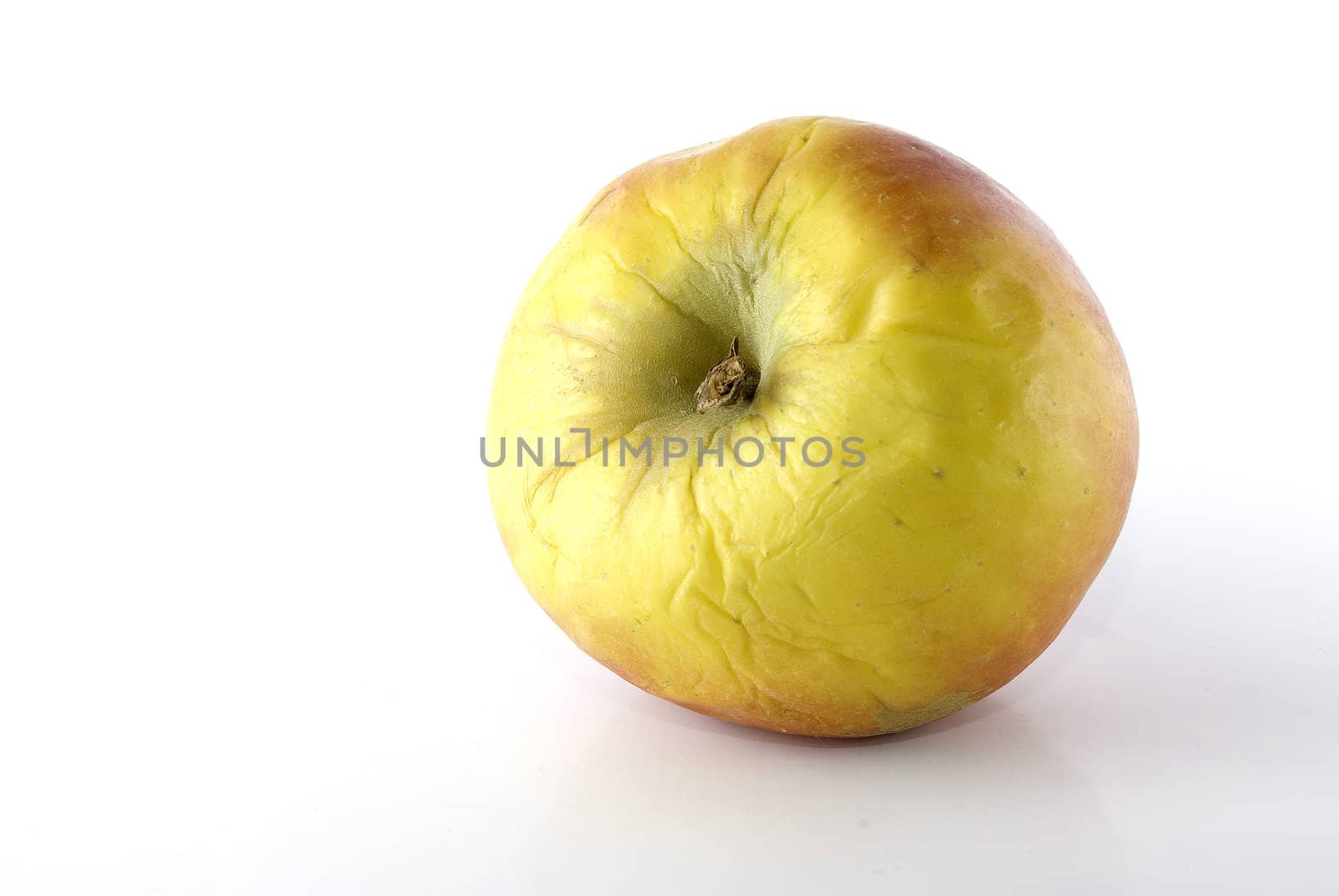 Wrinkled apple on white surface