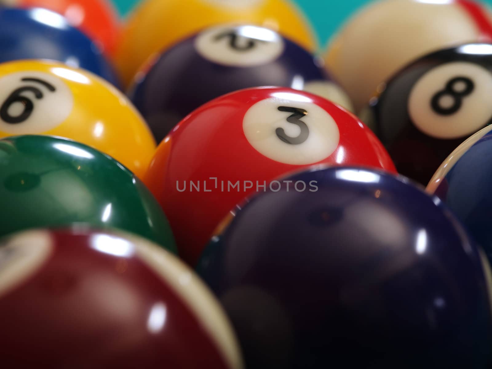 Macro photo of a pool table and billiard balls. Shallow depth of field with focus on the three ball.
