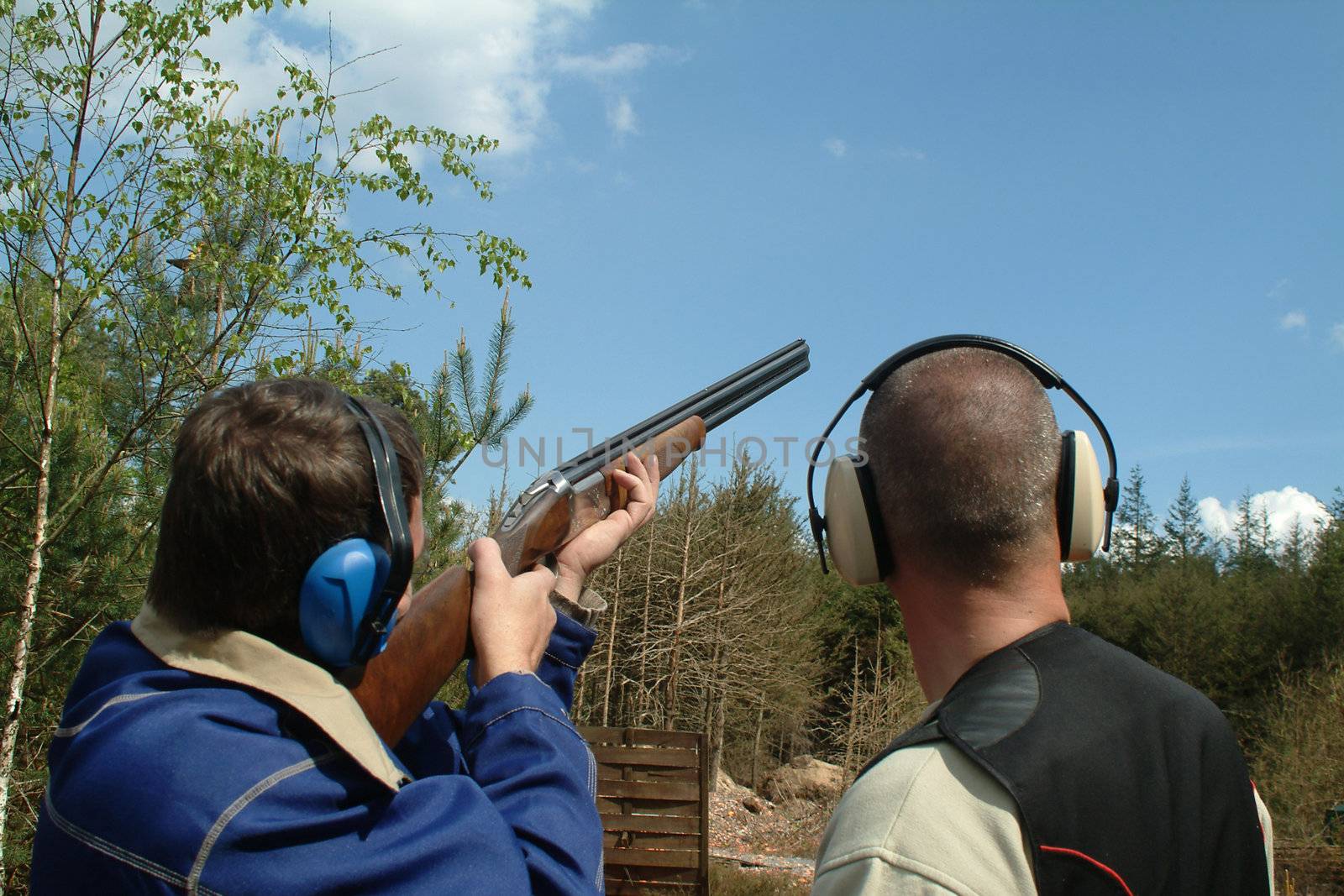 Man shooting clay pigeons being instructed