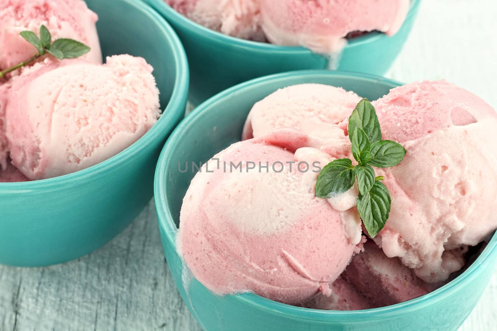 Three bowls of strawberry or raspberry sorbet, garnished with fresh mint.
