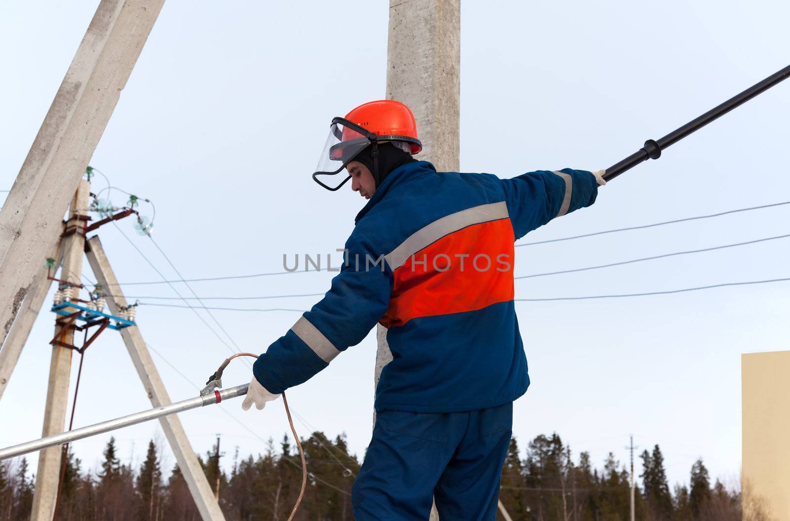 Electrician in blue overalls working on power lines