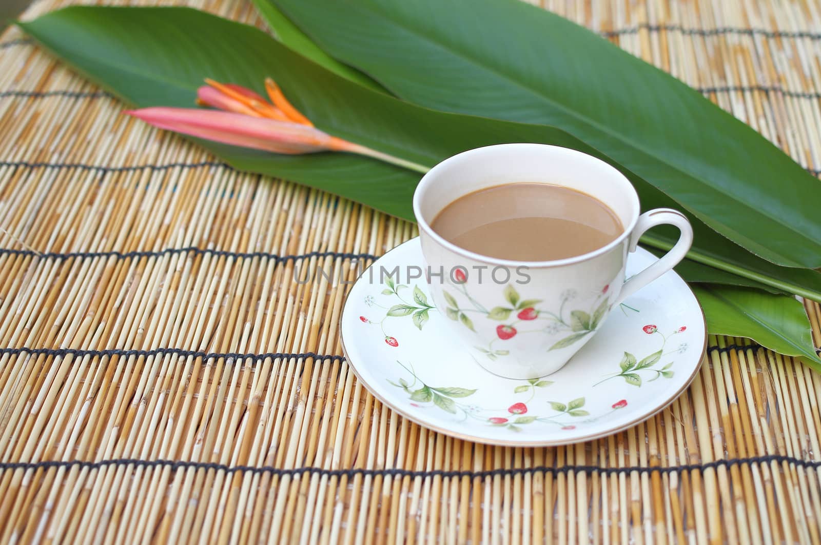 Cup of coffee with one heliconia flower, put on the table cloth made from wooden.