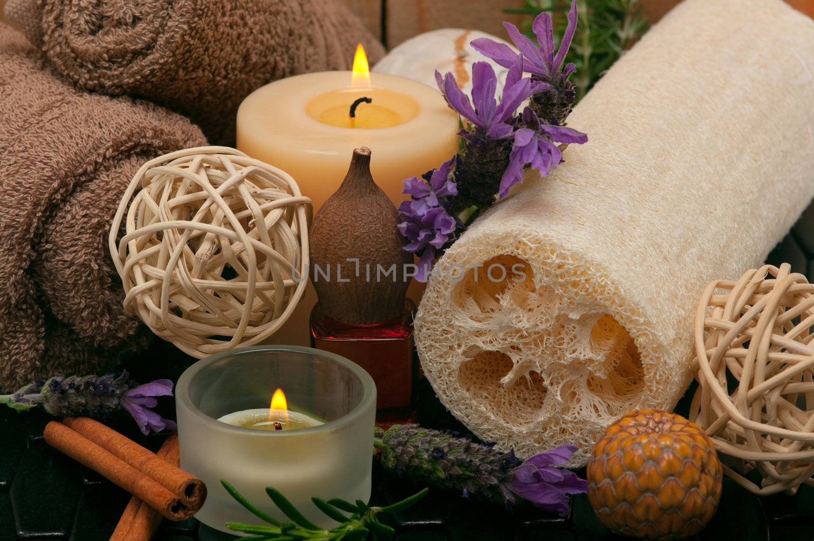 Spa concept with aromatic candles, lavender, massage oil, cotton towels and loofah