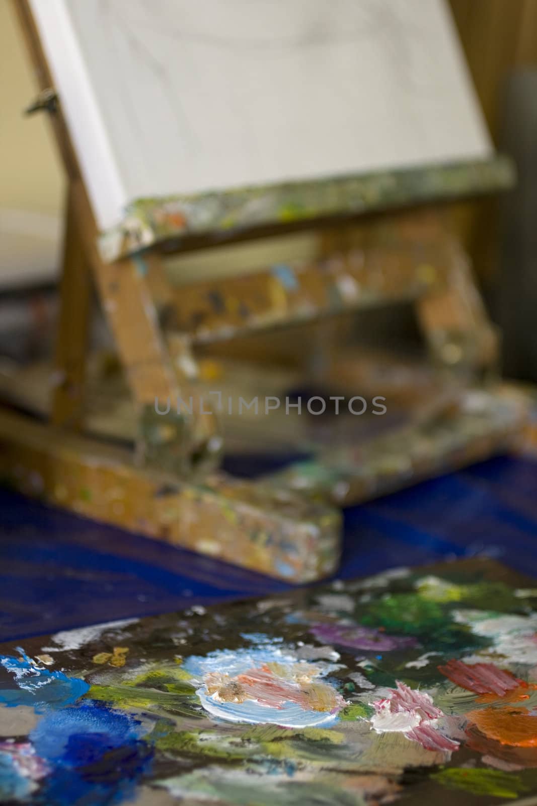 Atelier. Palette with colors, easel in the background