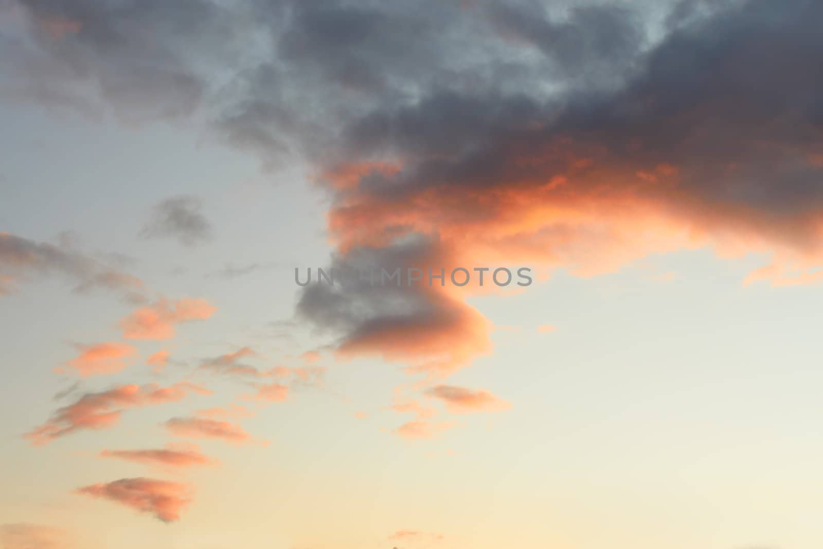 Reddish clouds during sunset on the background of pale blue sky