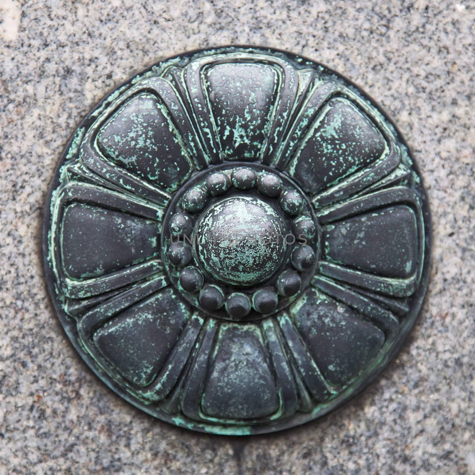 Close-up of decorative metal piece on granite wall.