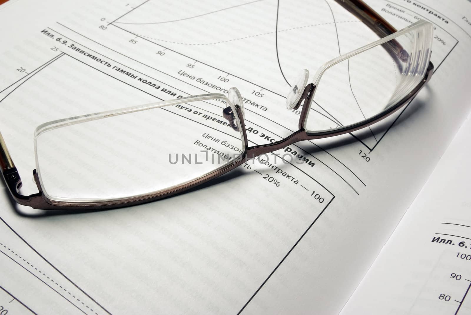 Glasses laying on book with financial charts. by borodaev