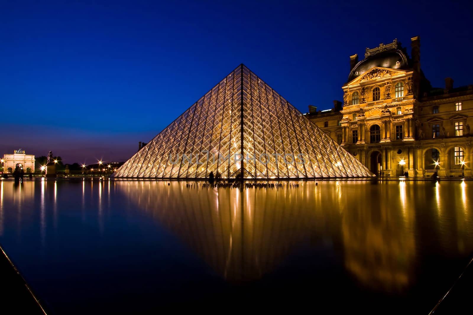 PARIS - APRIL 16: Reflection of Louvre pyramid shines at dusk during the Summer Exhibition April 16, 2010 in Paris. This is one of the most popular tourist destinations in France.