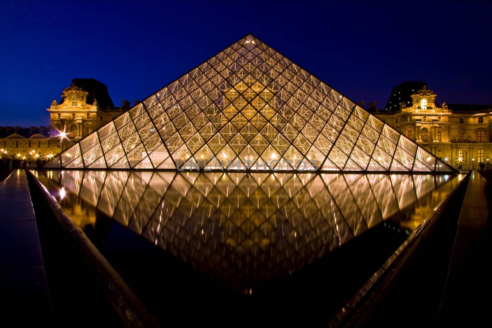 PARIS - APRIL 16: Reflection of Louvre pyramid shines at dusk during the Summer Exhibition April 16, 2010 in Paris. This is one of the most popular tourist destinations in France.