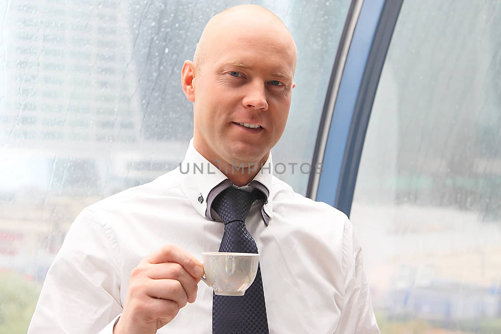The businessman drinks coffee at office from a small white cup