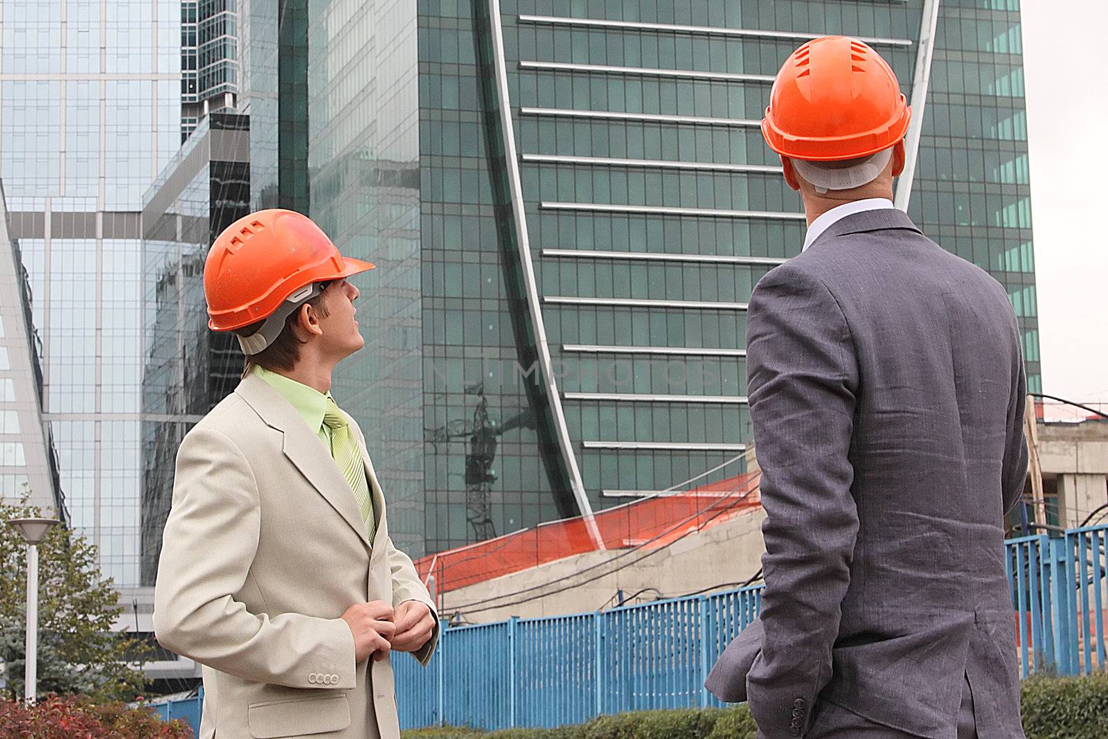 Two businessmen in business suits and helmets on building