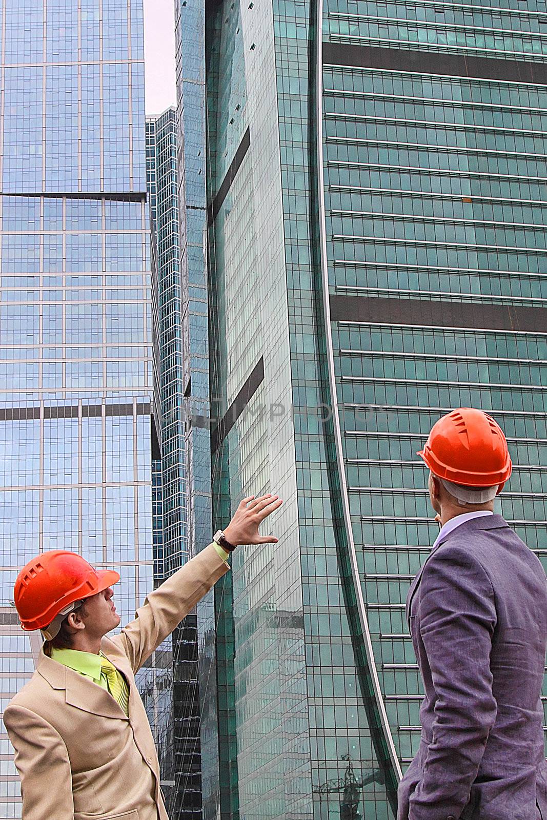 Two businessmen in business suits and helmets on building