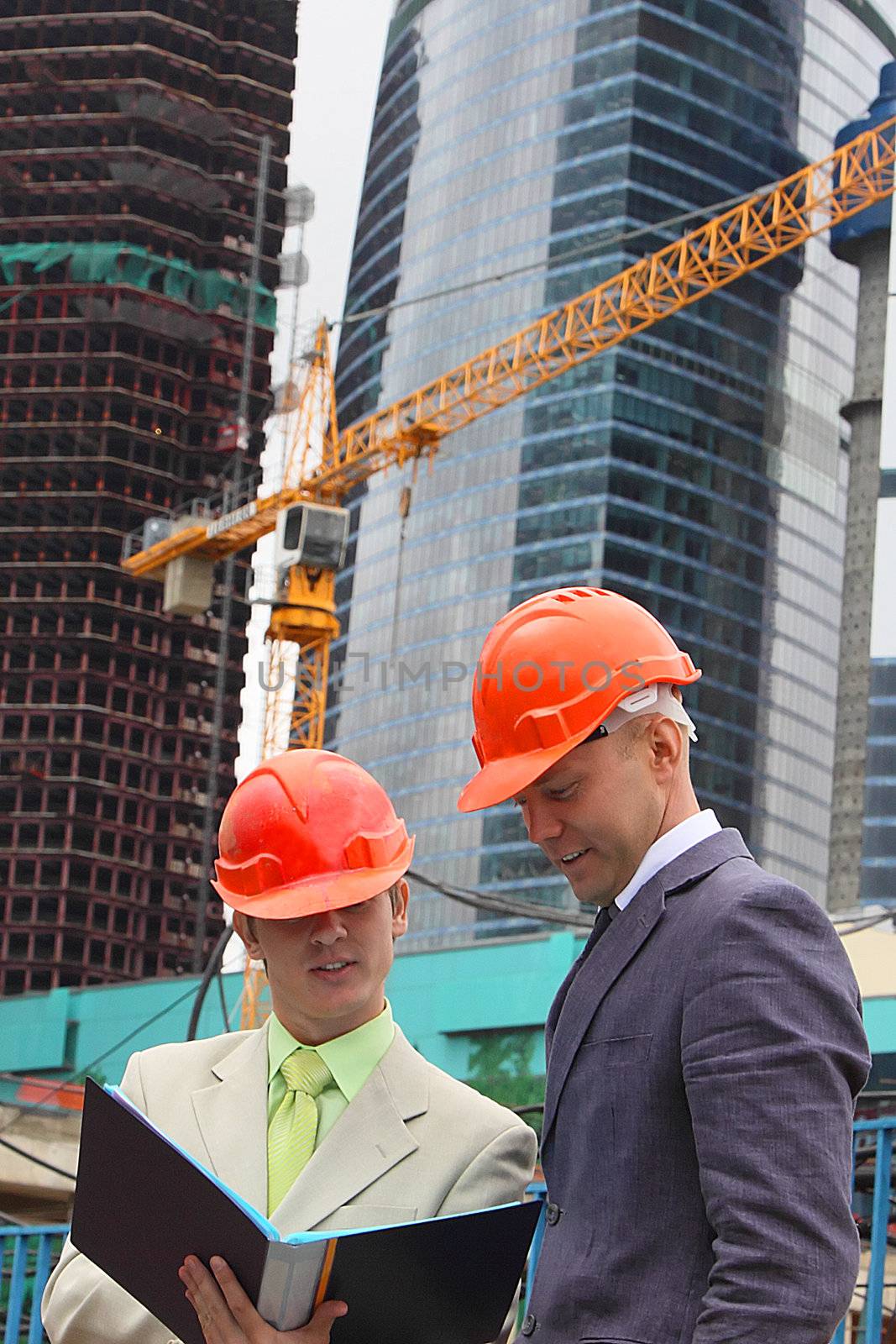 Two businessmen in business suits and helmets on building