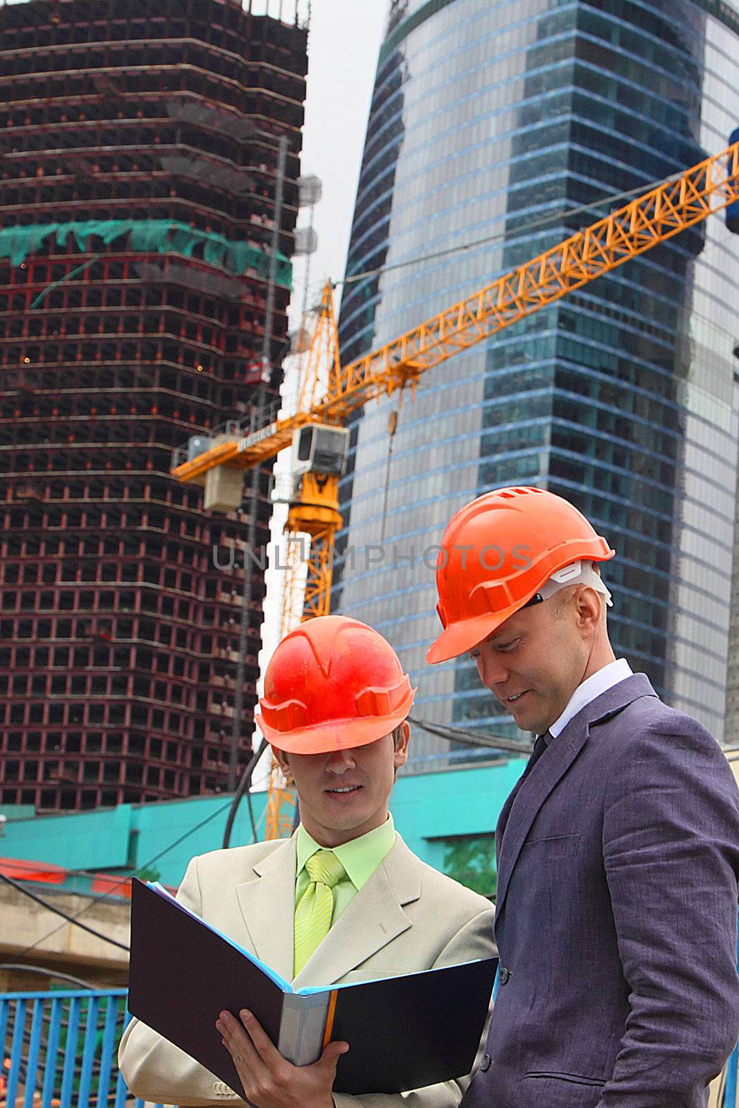 Two businessmen in business suits and helmets on building