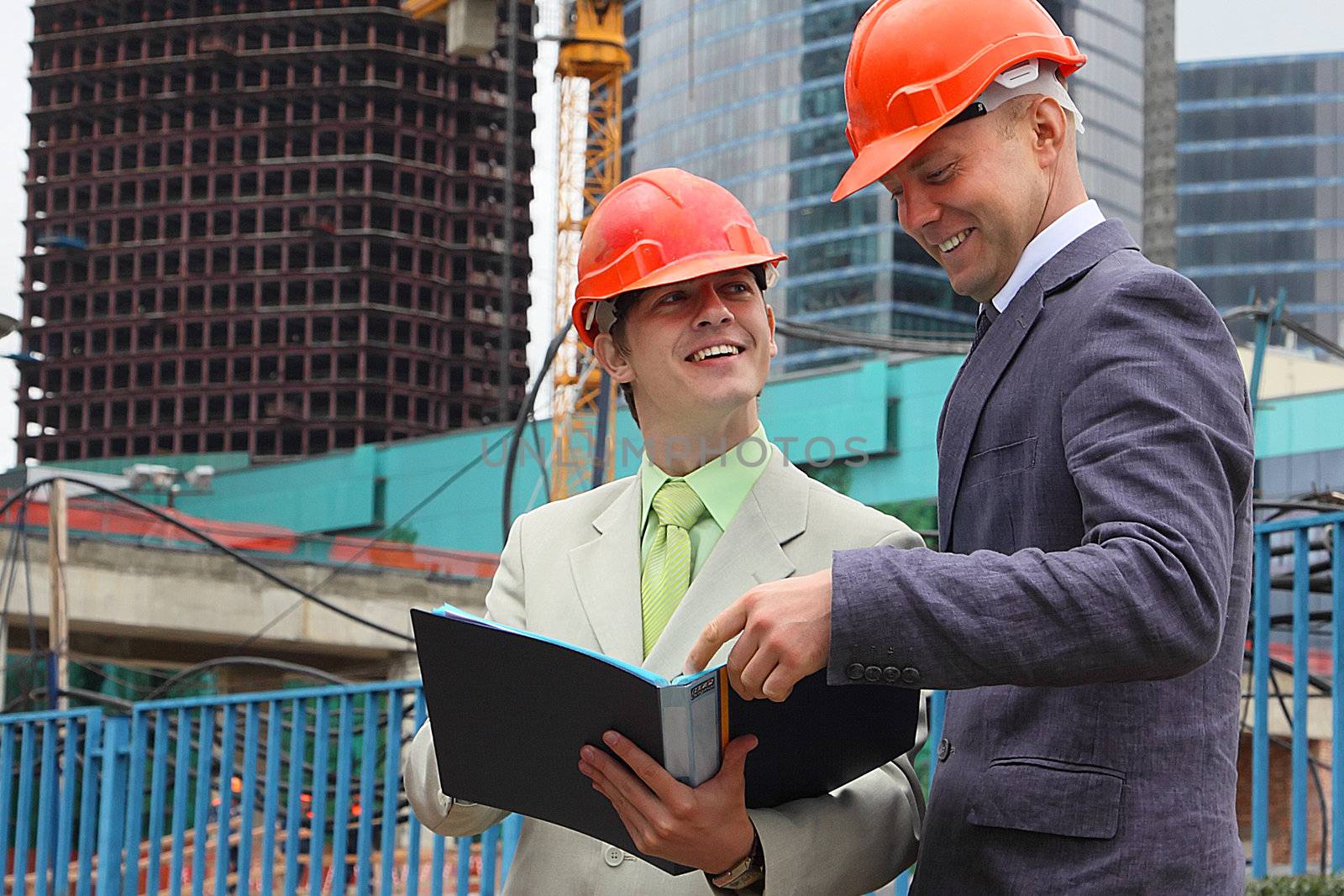 Two businessmen in business suits and helmets on building