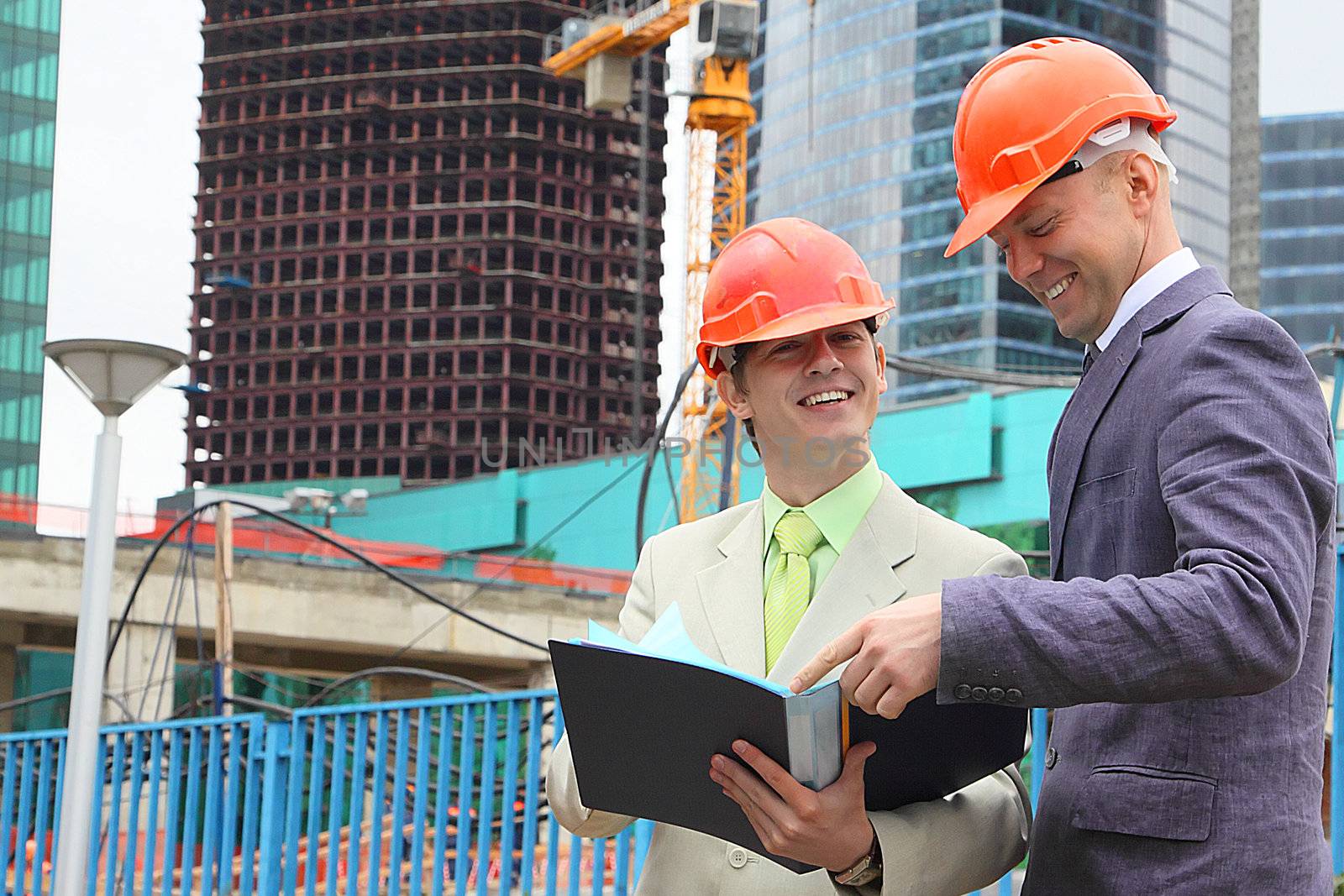 Two businessmen in business suits and helmets on building