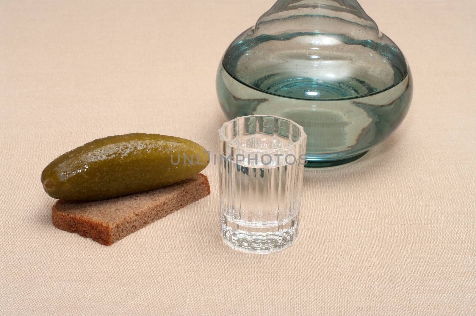 Wineglass of vodka pickles and rye bread close up.