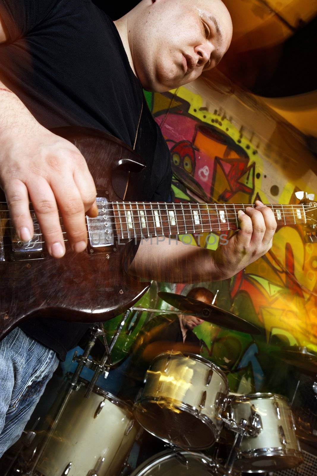 Band playing on a stage. Shot with strobes and slow shutter speed to create lighting atmosphere and blur effects. Slight motion blur on performers.
