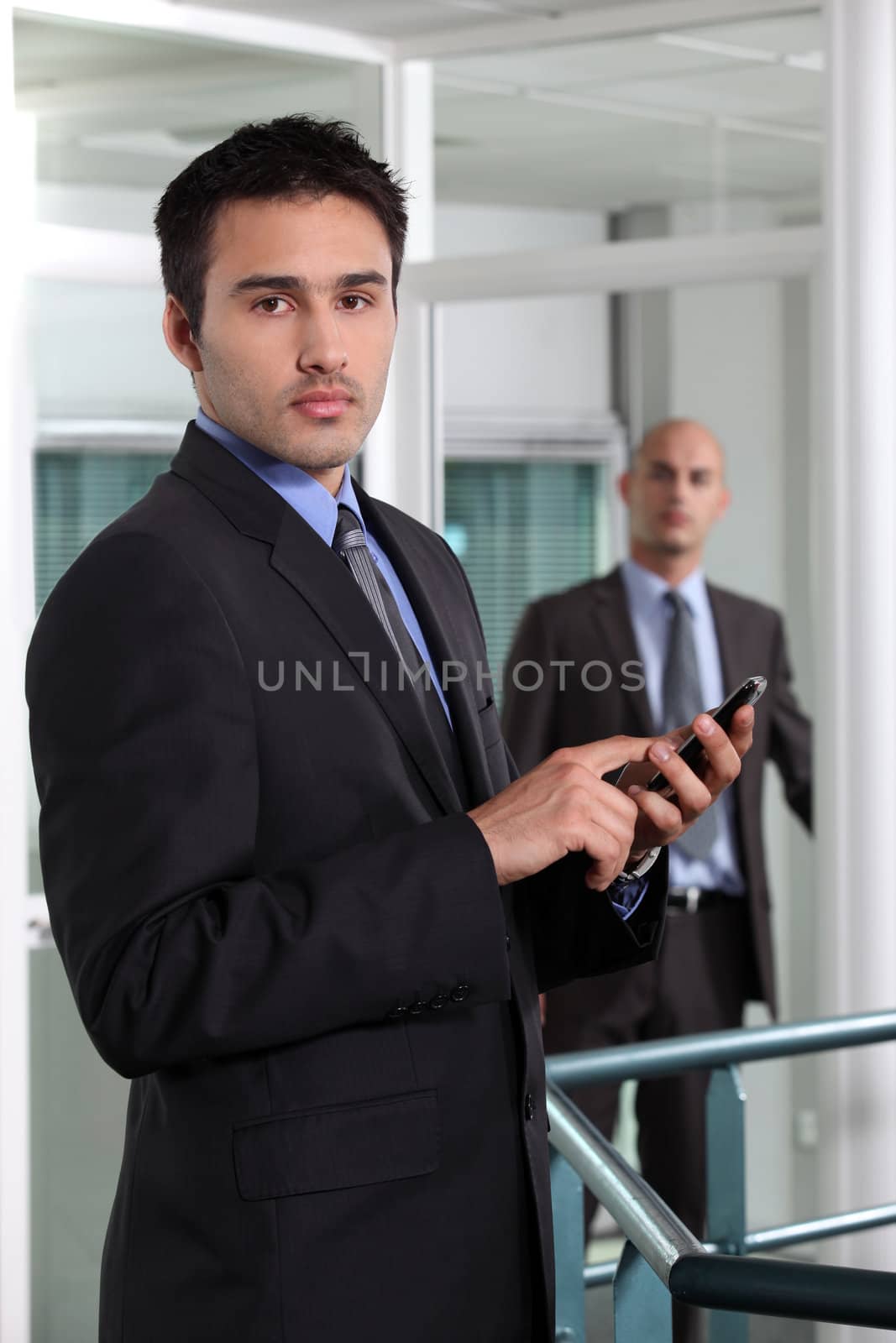 businessman at the office holding a cell phone by phovoir