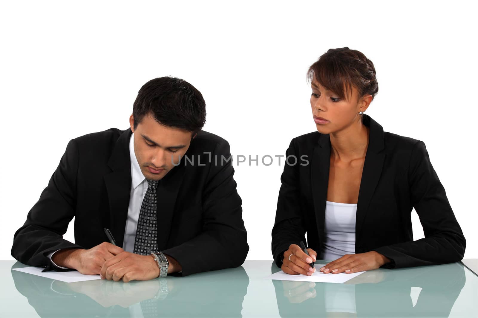 Two businesspeople writing at a desk by phovoir