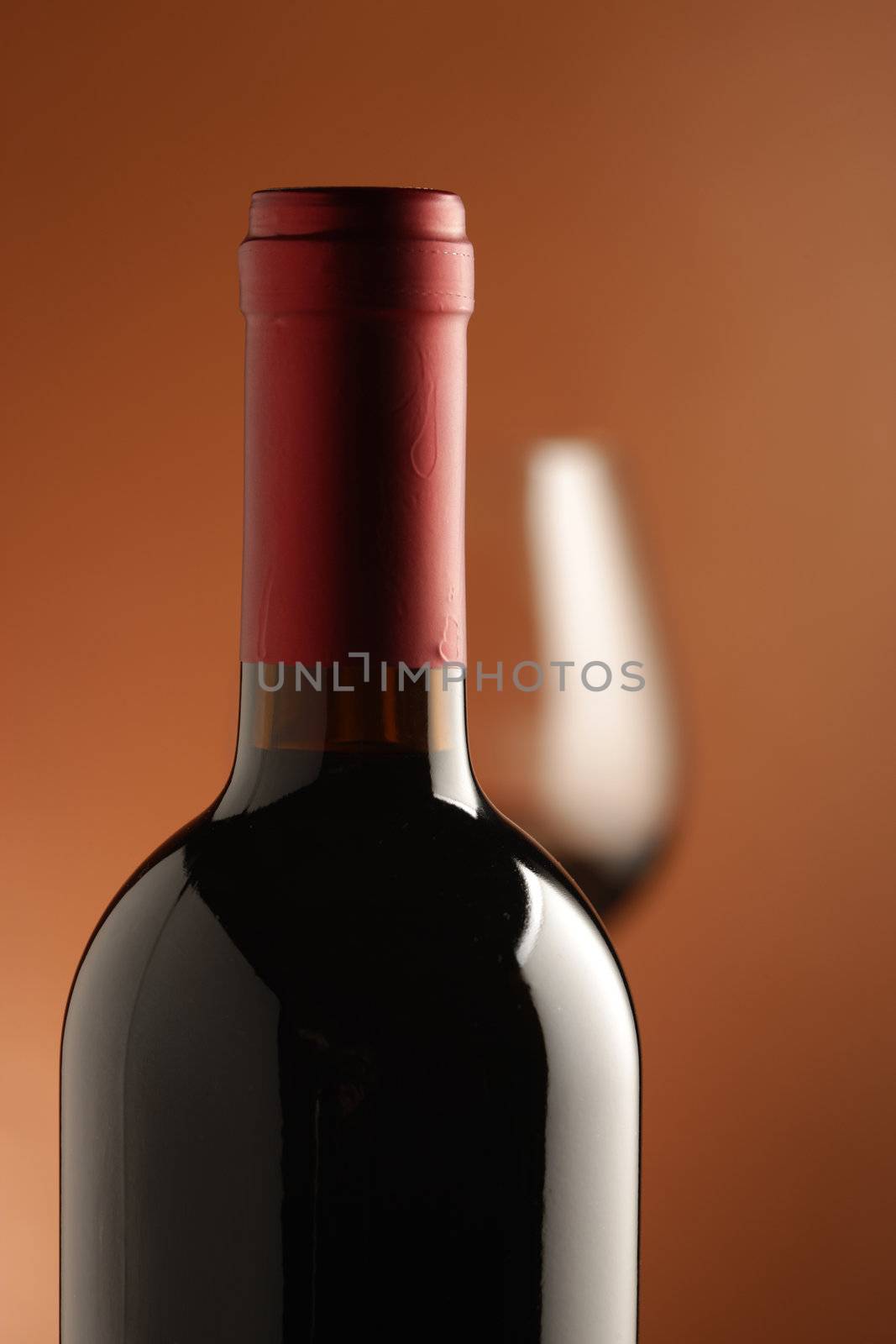 red wine bottle and a wine glass at background.(Shallow DOF)