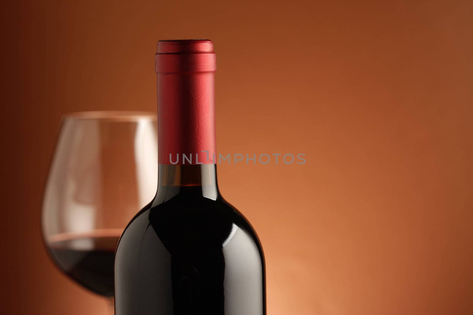 red wine bottle and a wine glass at background.(Shallow DOF)