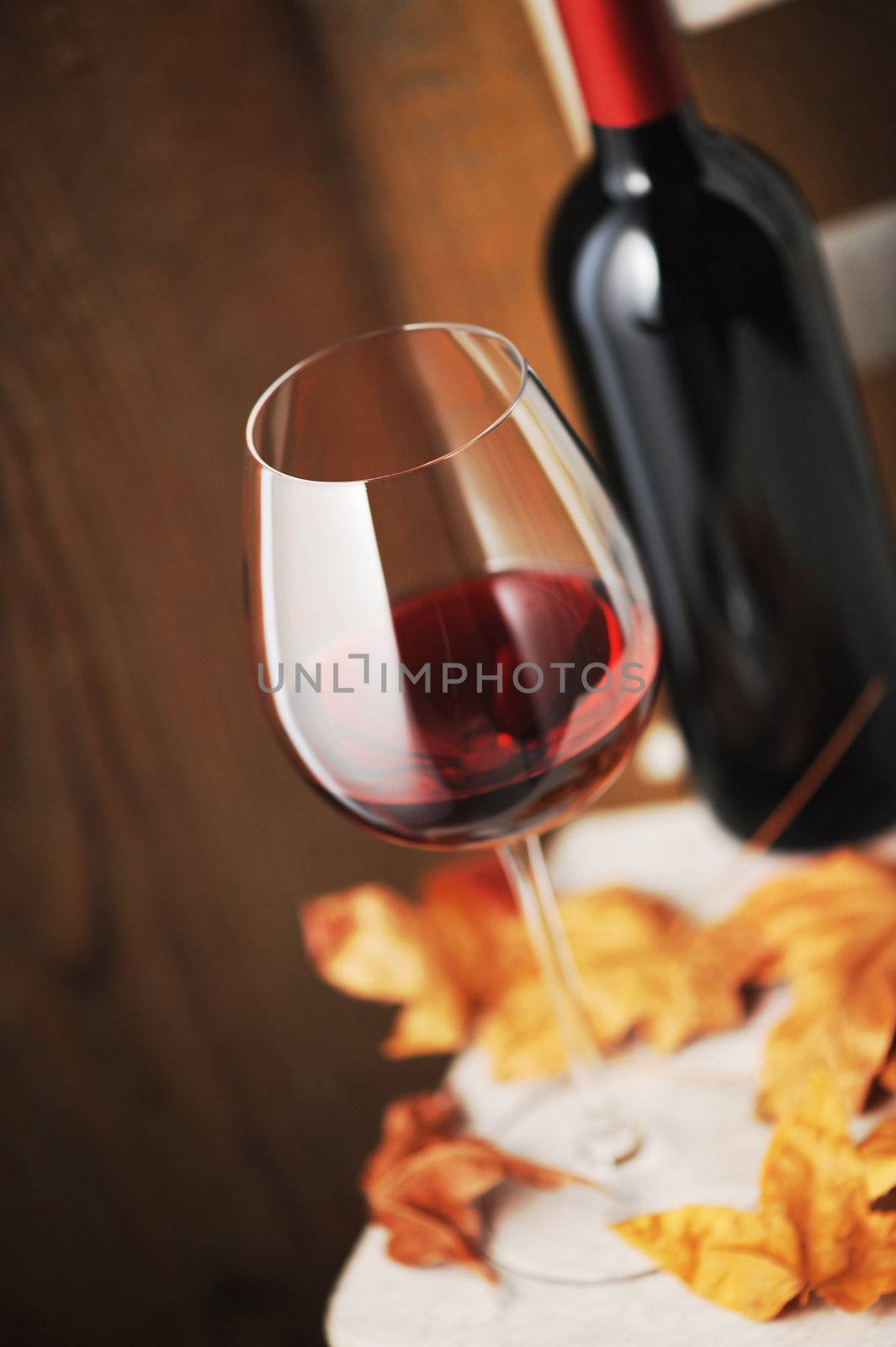  glass of red wine and a bottle of red wine on background (shallow dof)