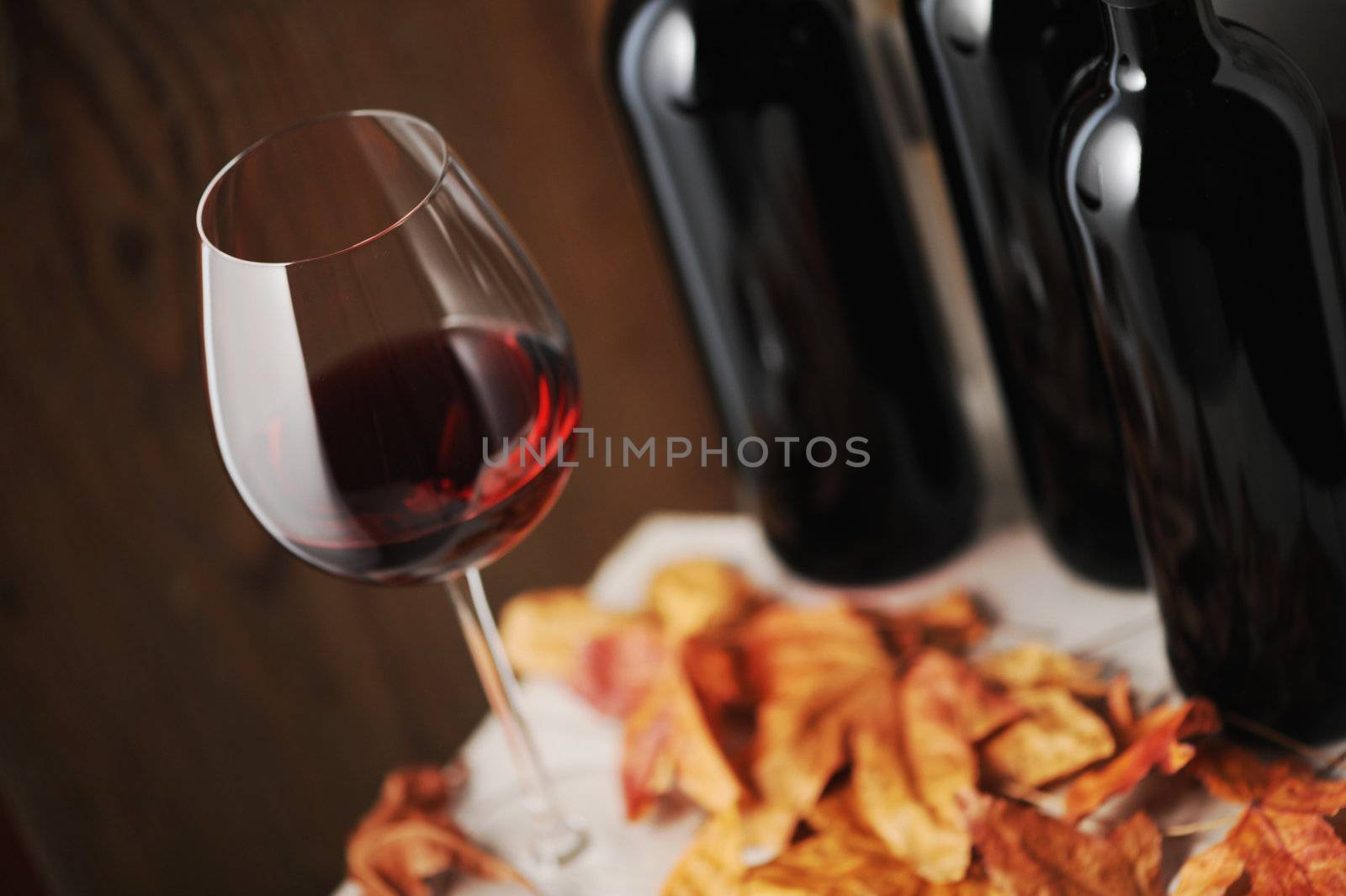  glass of red wine and a bottle of red wine on background (shallow dof)