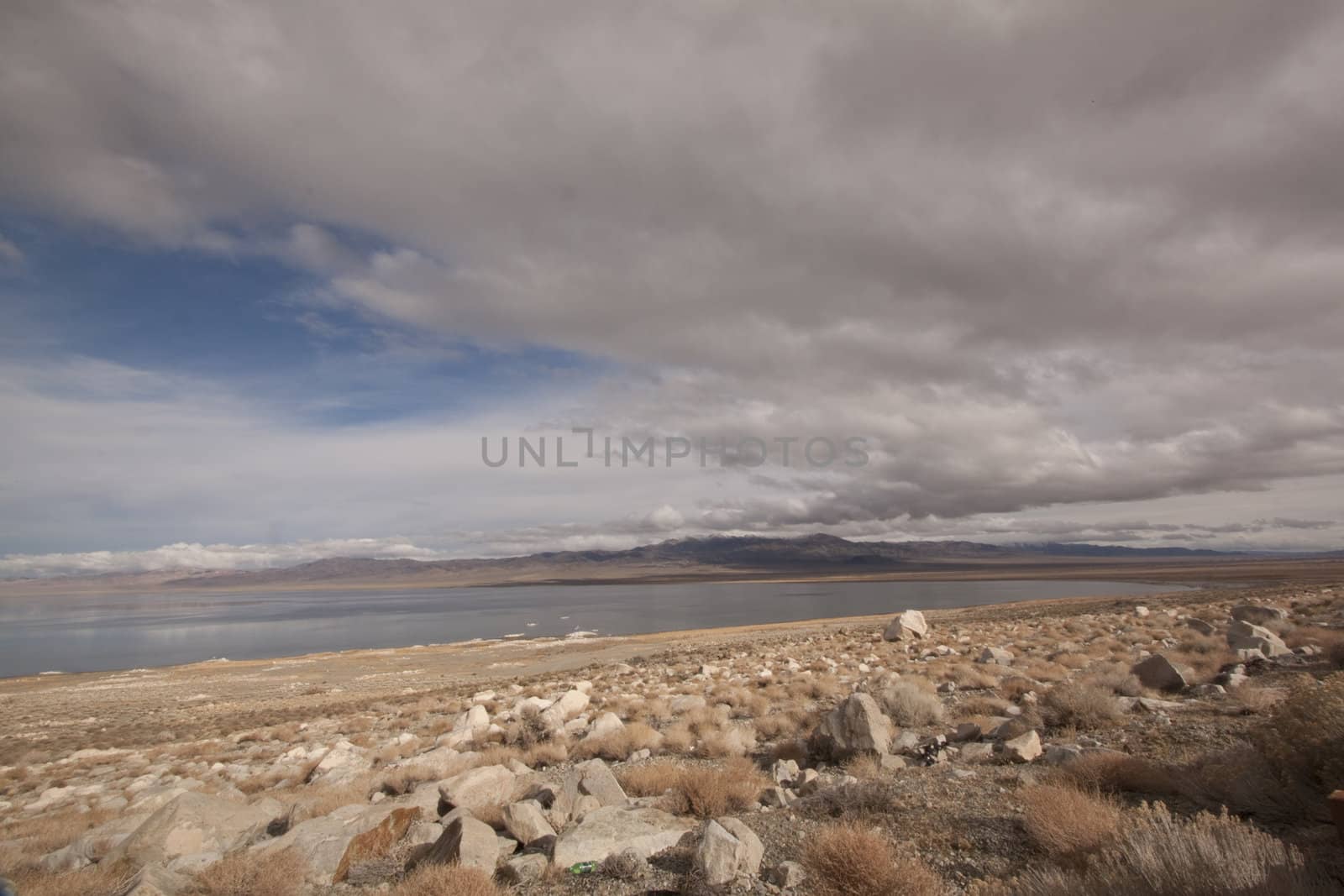 A lonely highway by a desert mountain range and lake