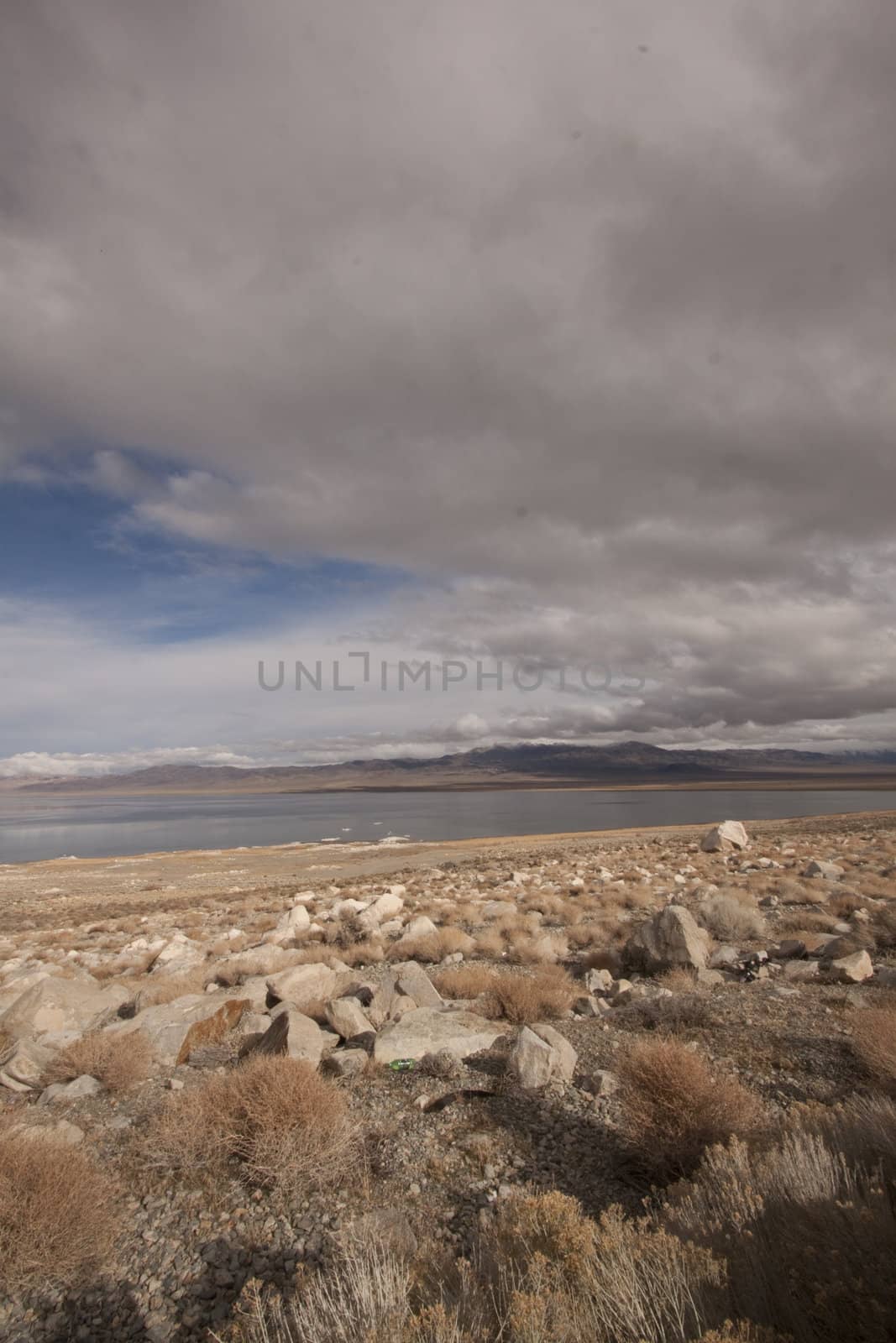 A lonely highway by a desert mountain range and lake