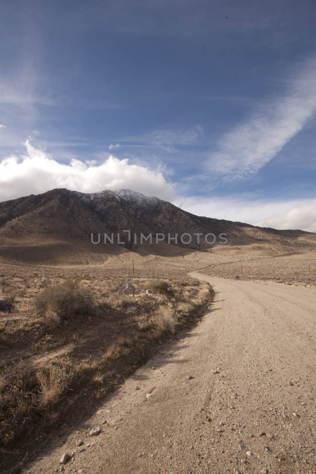 A lonely highway by a desert mountain range and lake