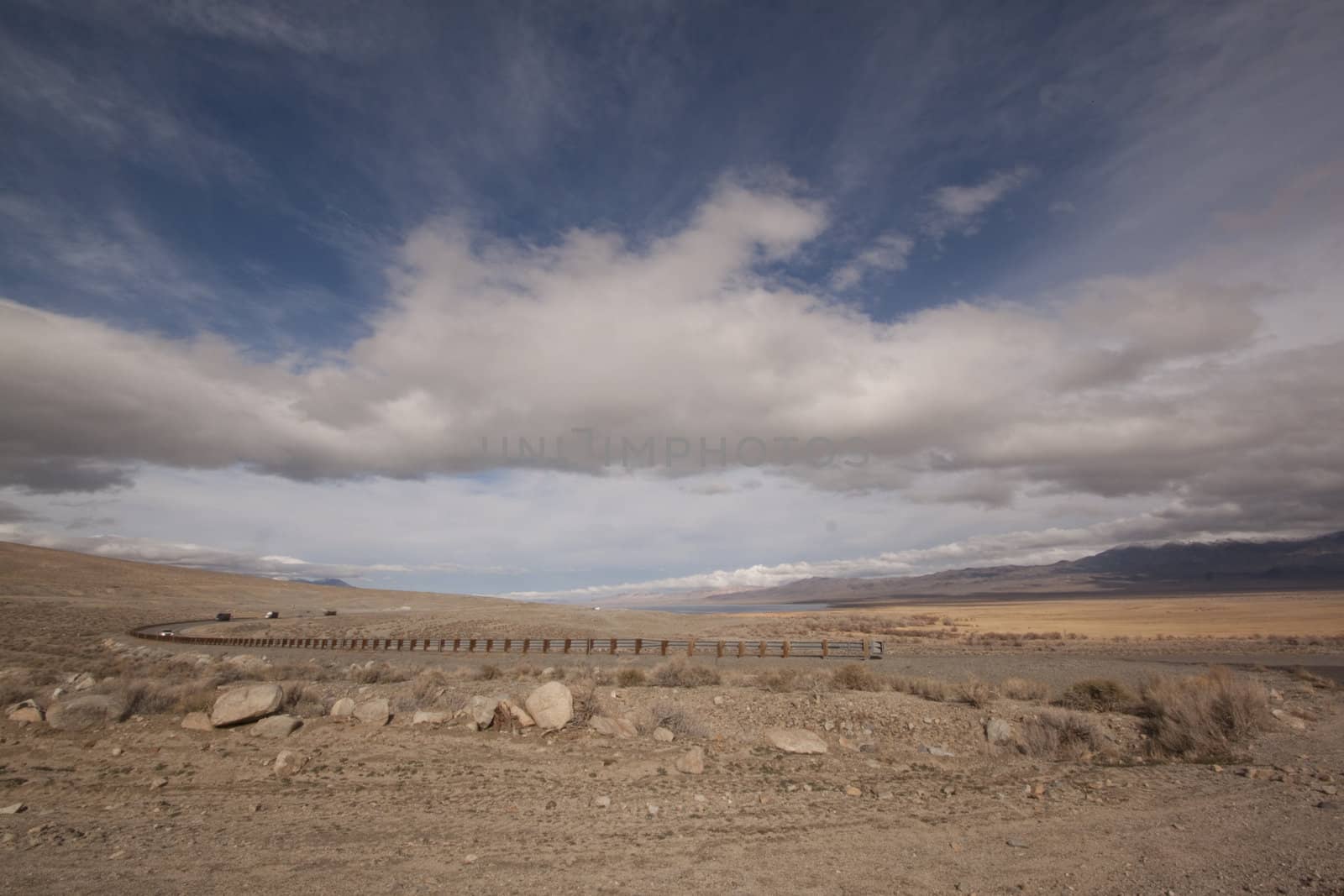 A lonely highway by a desert mountain range and lake