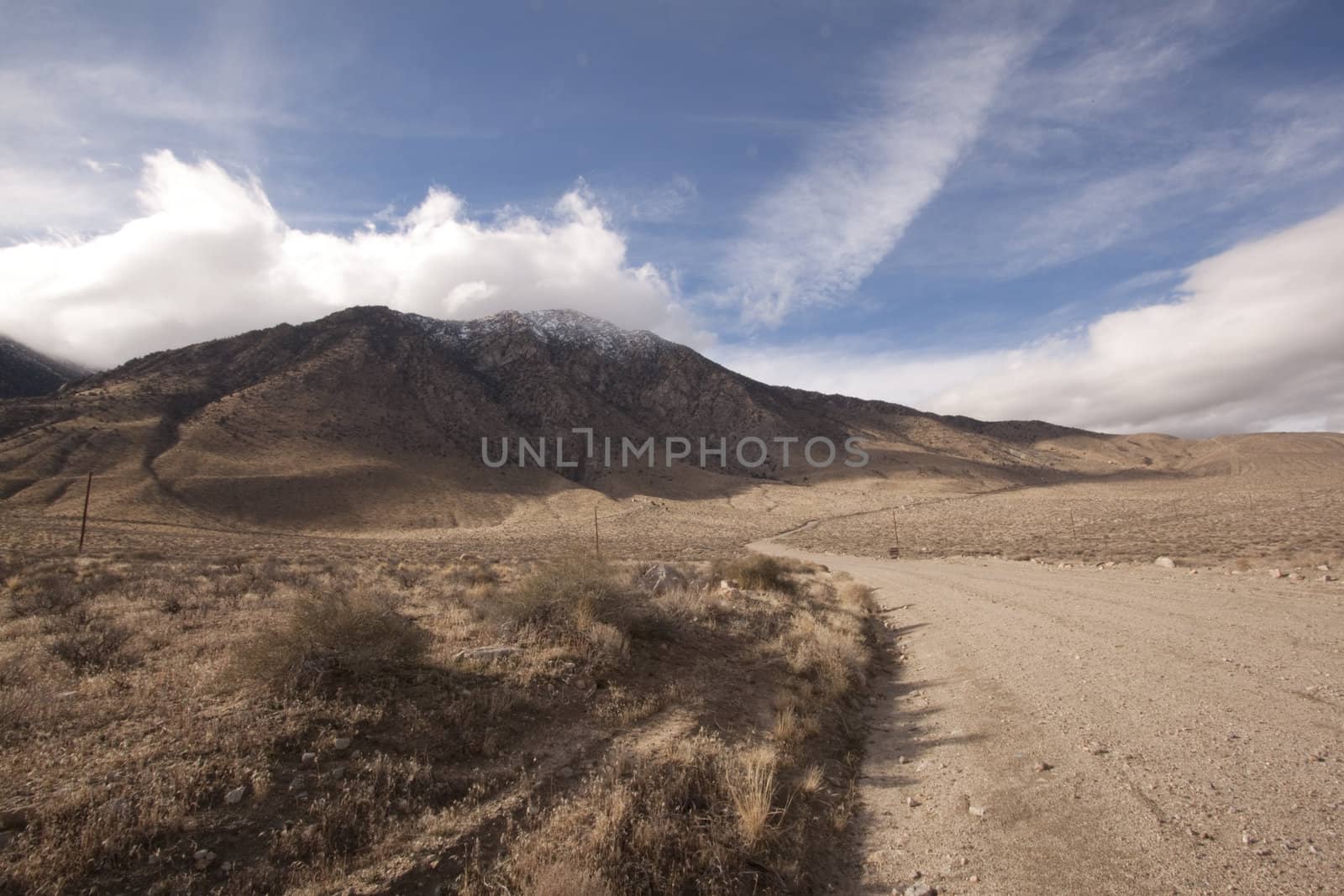 A lonely highway by a desert mountain range and lake