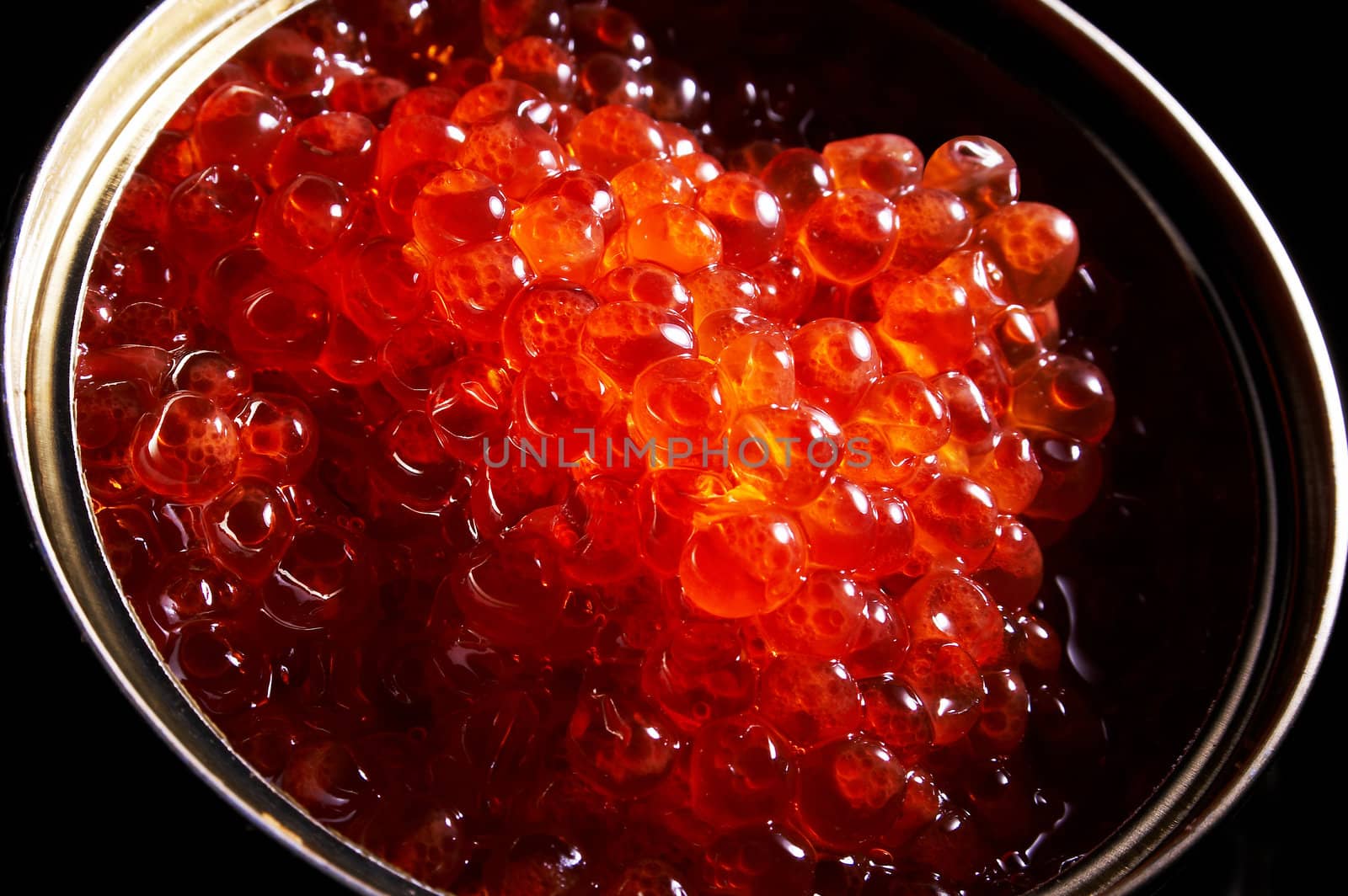 Red caviar in a can on a black background