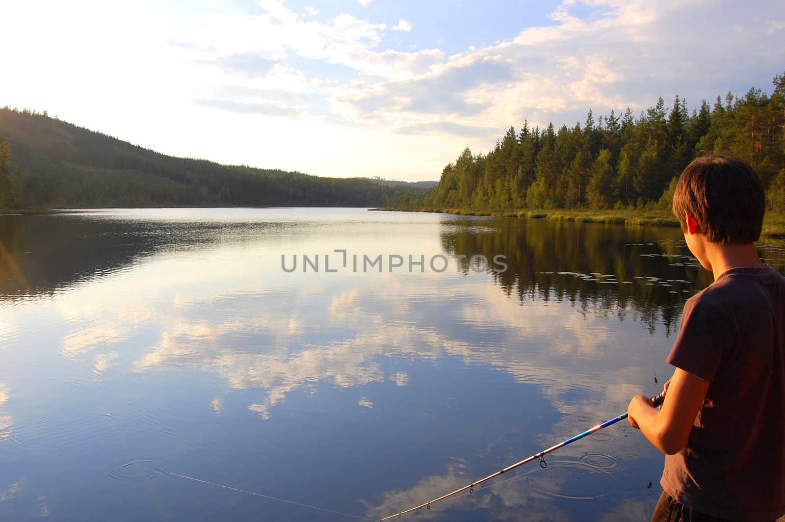 A boy fishing on a nice summerevening in Värmland, Sweden.