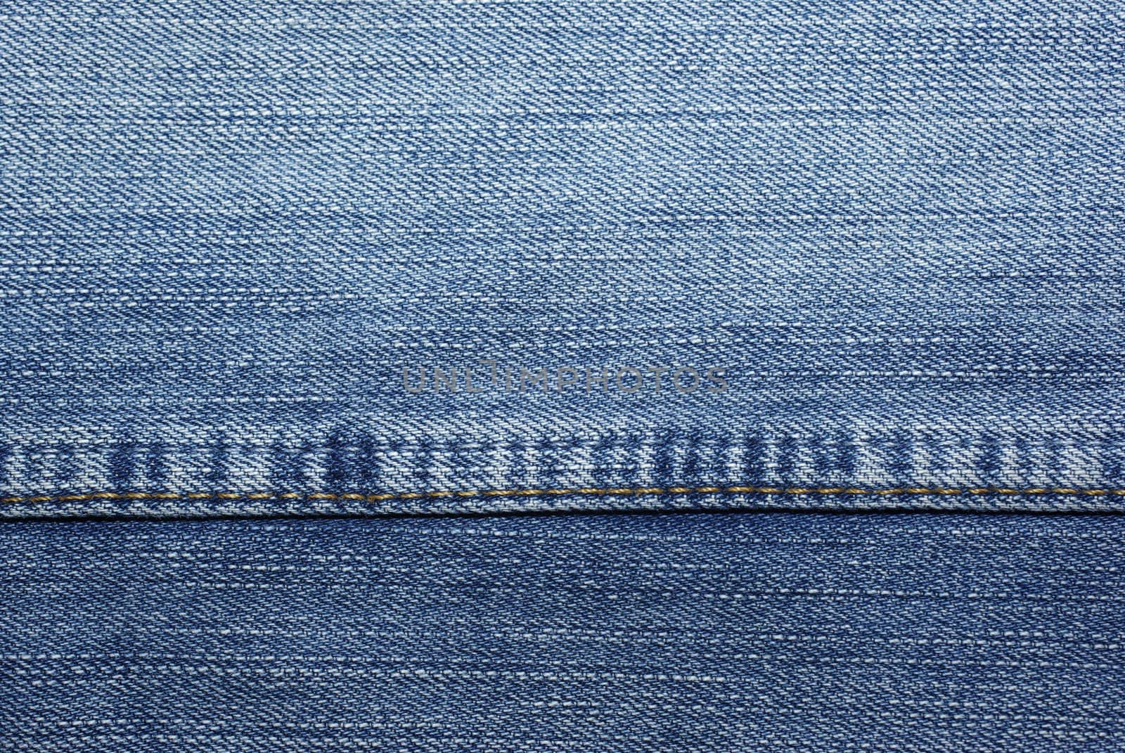 Blue jeans with yellow stitches as background or backdrop. by borodaev