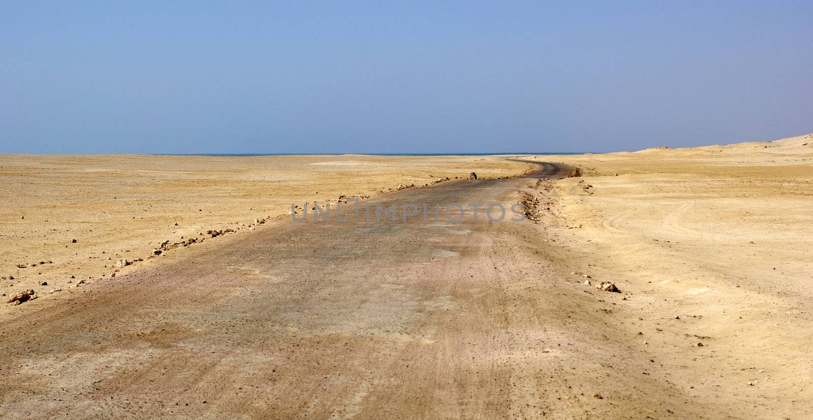 Road in desert and Red sea over horizon. Egyptian national reserve, Africa.