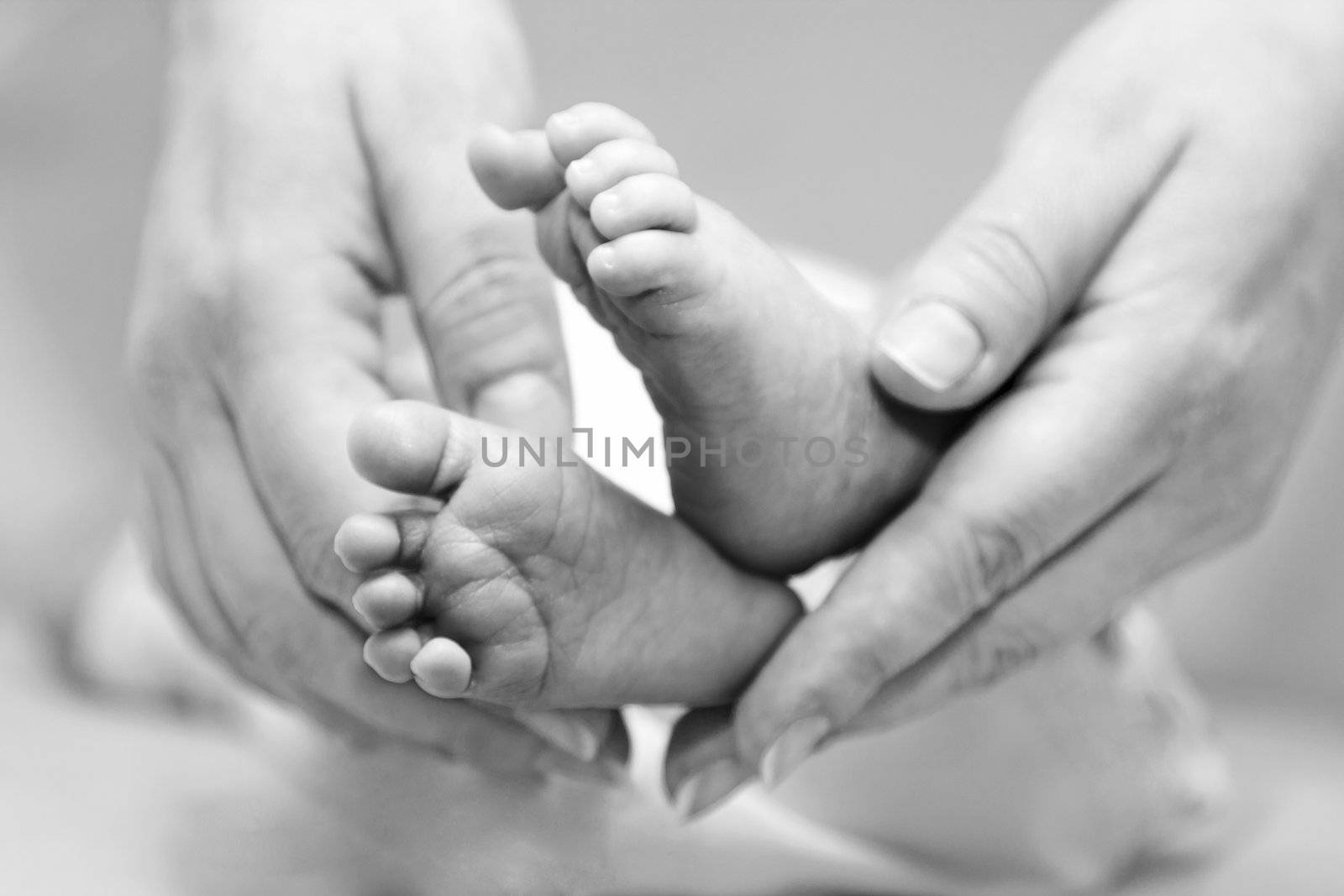 Mother's gentle touch holding cute baby feet.
