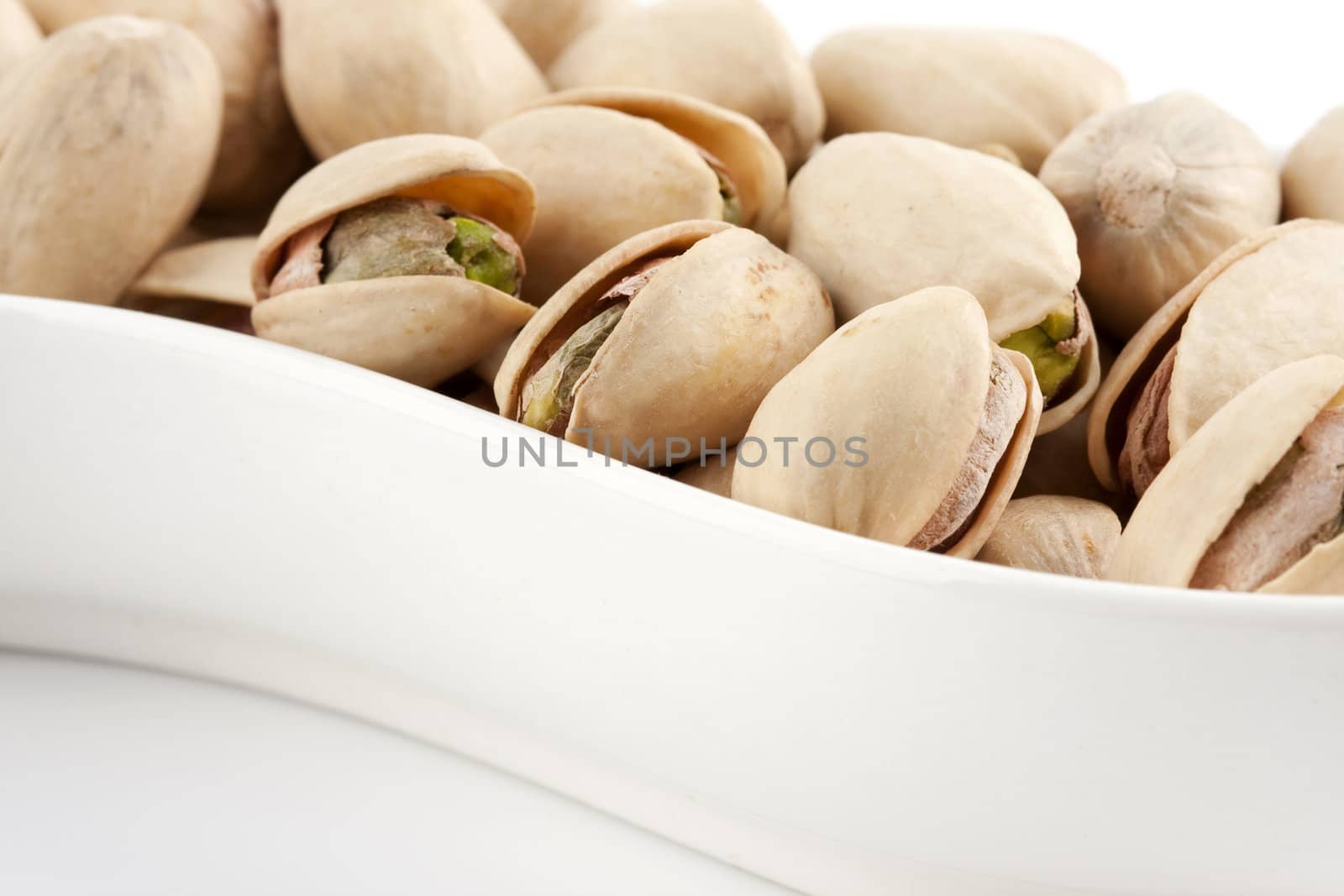 Close-up roasted and salted pistachios on white plate